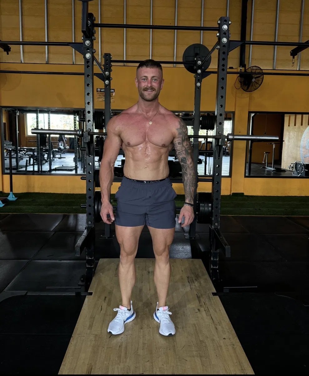 Coach Myles standing in front of a squat rack in the gym